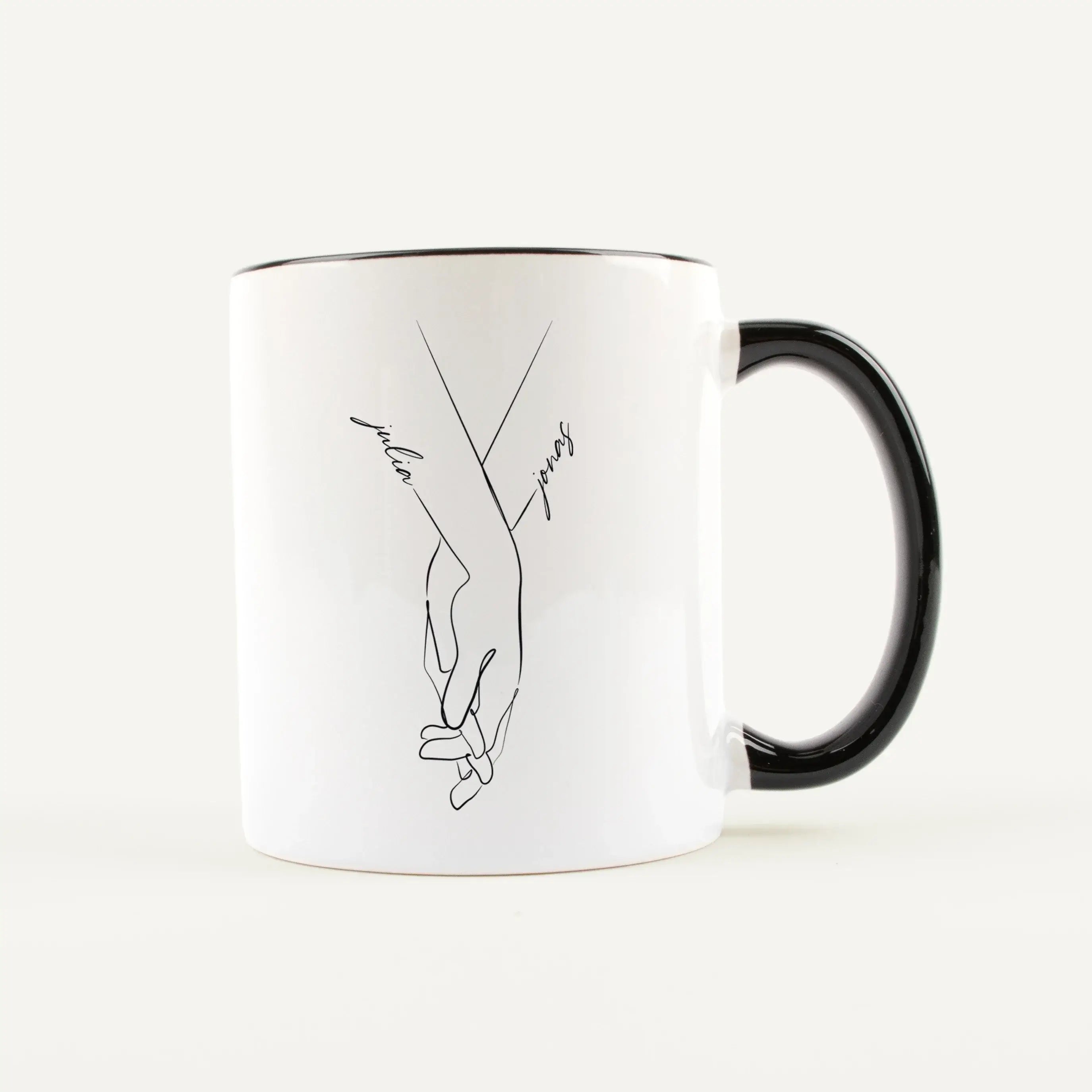 Tasse Hand in Hand-Keramik Tasse-famprints-Tasse Hand in Hand von famprints ist eine persönliche Tasse für Paare, die ein schlichtes Motiv mit Bedeutung suchen. Zwei ineinandergreifende Hände stehen für Verbundenheit, während die Namen direkt in das Desig